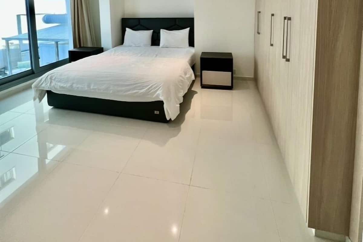 A modern bedroom with a large bed, a wardrobe, and a view of the outside.