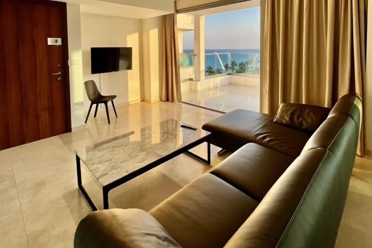 A modern living room with a leather sofa, a glass coffee table, and a flat-screen TV.