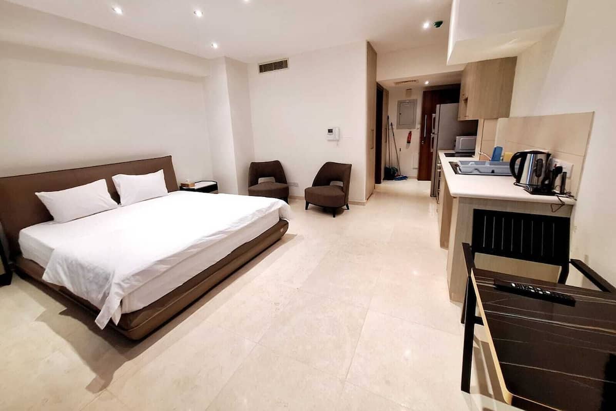 A hotel room with a large bed, a desk with a computer, and two chairs.