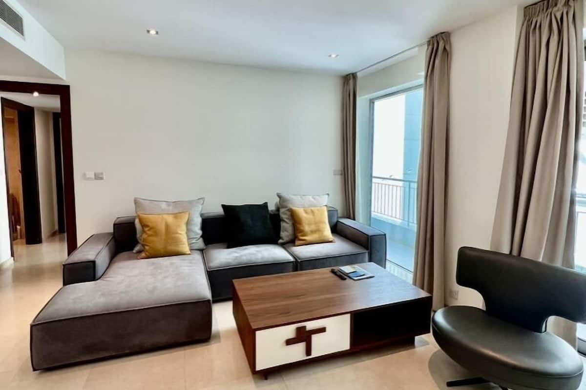 A modern living room with a sectional sofa, a coffee table with a cross design, and a black chair.