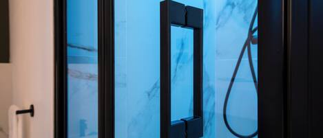 Une salle de bain avec une douche à parois de verre, un porte-serviettes et un mur en marbre.