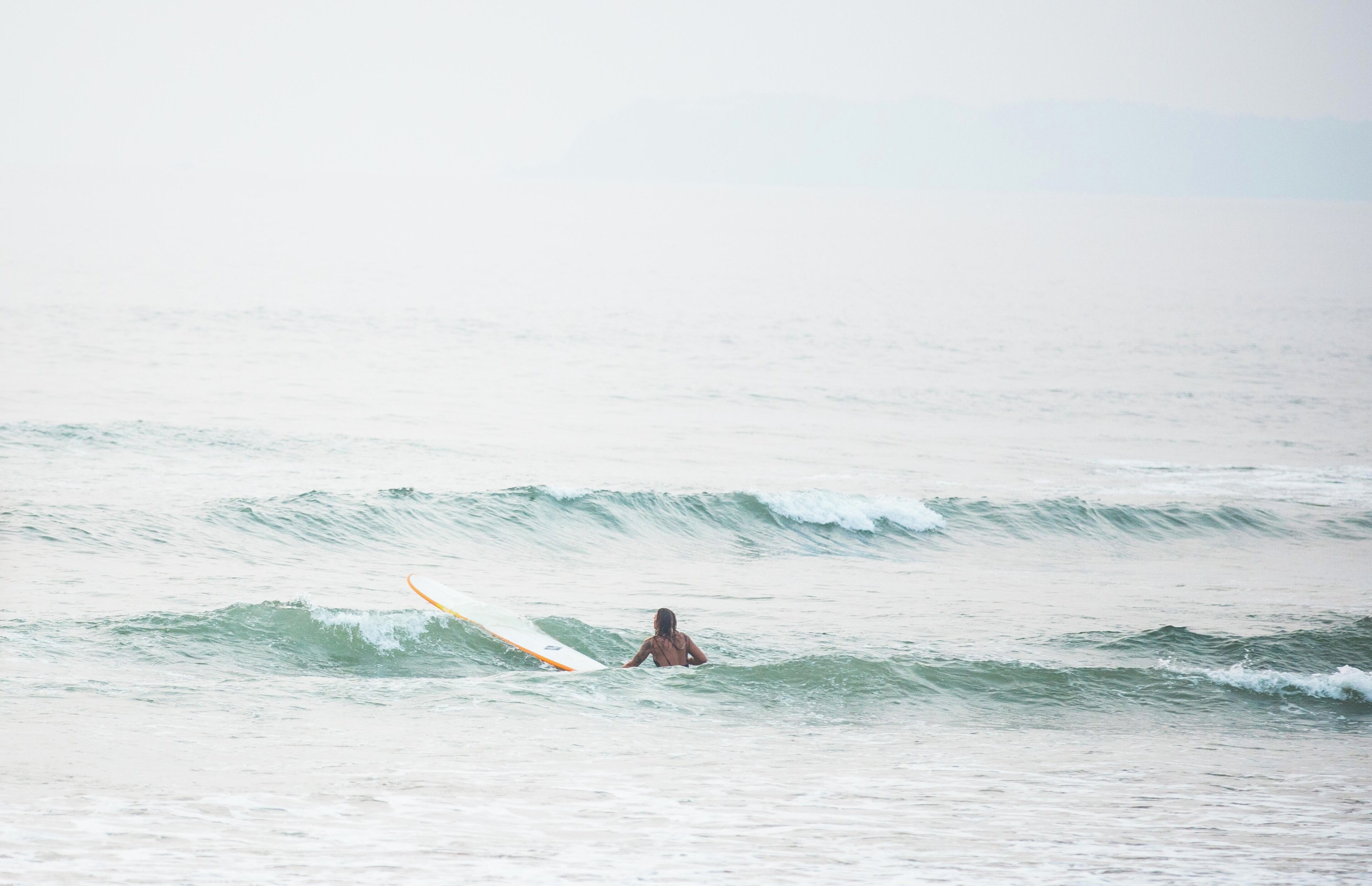 A person in the ocean with a surfboard.