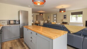 A modern kitchen with grey cabinets, a wooden countertop, and a built-in microwave. - Tawny's Roost (King's Lynn)