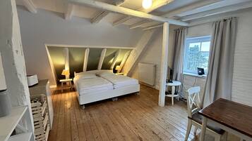 A bedroom with a sloped ceiling, a bed, a desk, and a chair.