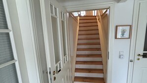 Ein Flur mit einer Holztreppe, die zu einer Tür führt.