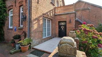 A brick building with a black door, a staircase, and potted plants.