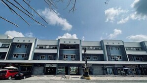 A multi-story commercial building with a flat facade, storefronts on the ground level, and a clear sky with clouds. - Daraga Tourist Inn (Daraga)