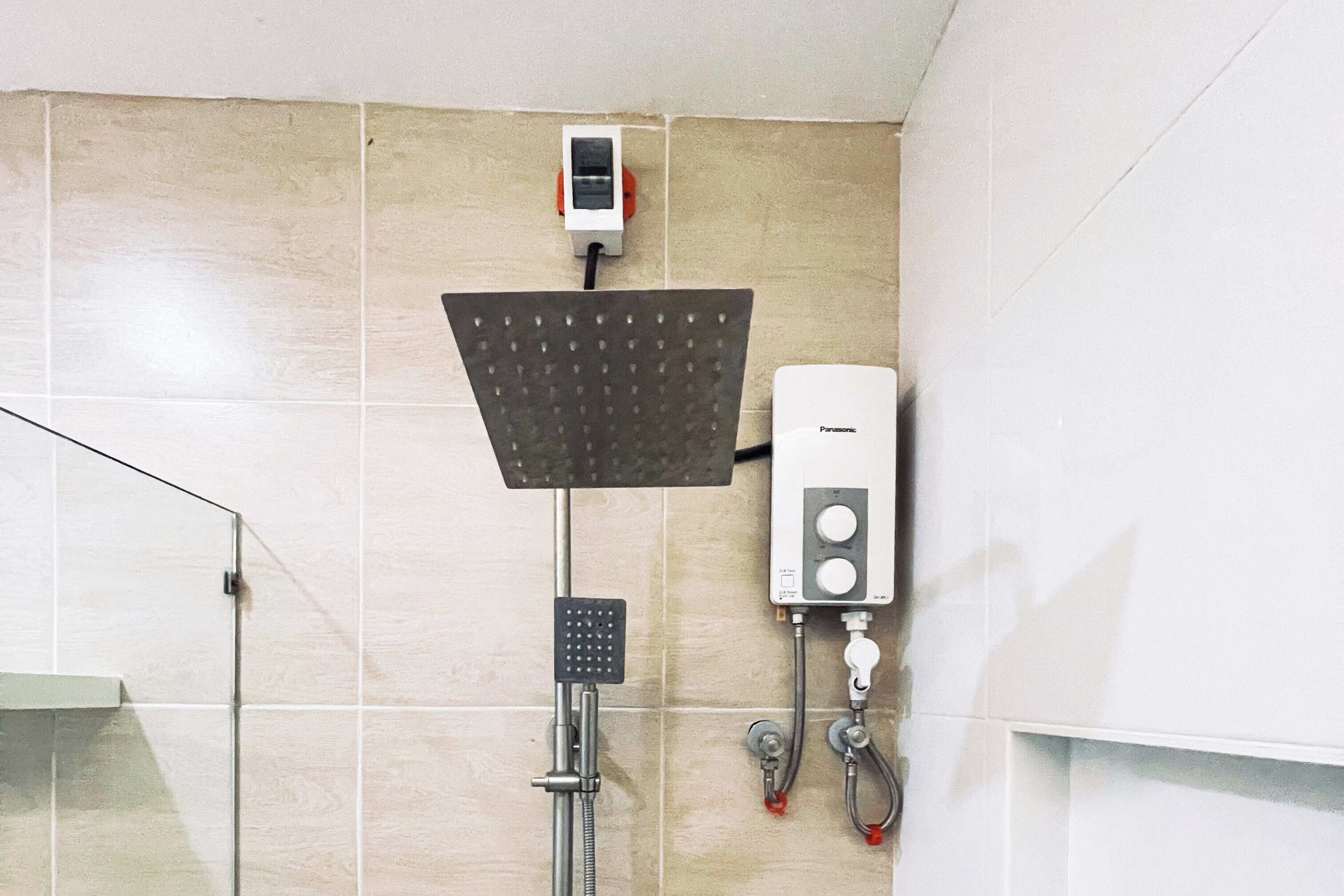 Un baño con ducha, inodoro y panel de control en la pared.