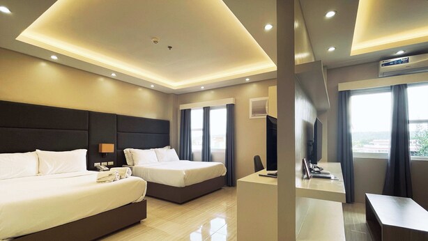 A hotel room with two beds, a desk, a chair, and a large window. - Daraga Tourist Inn (Daraga)