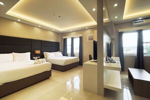 Habitación de hotel con dos camas, un escritorio, una silla y un ventanal grande.