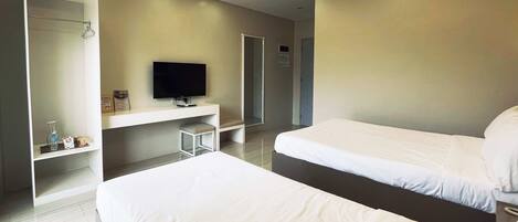 A modern hotel room with two beds, a flat-screen TV, a small seating area, and a walk-in closet.
