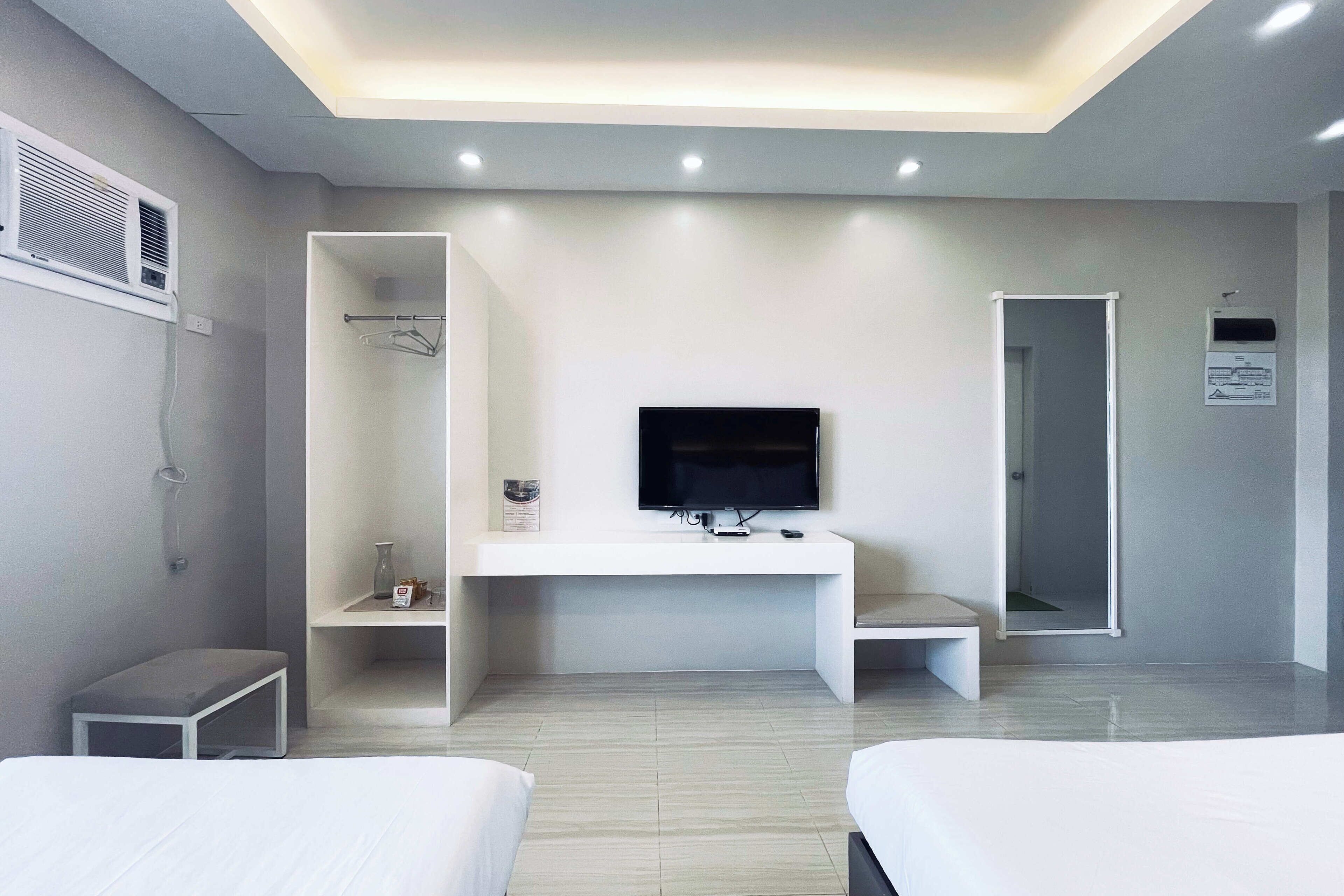 A modern hotel room with a flat-screen TV, a desk, and two beds.