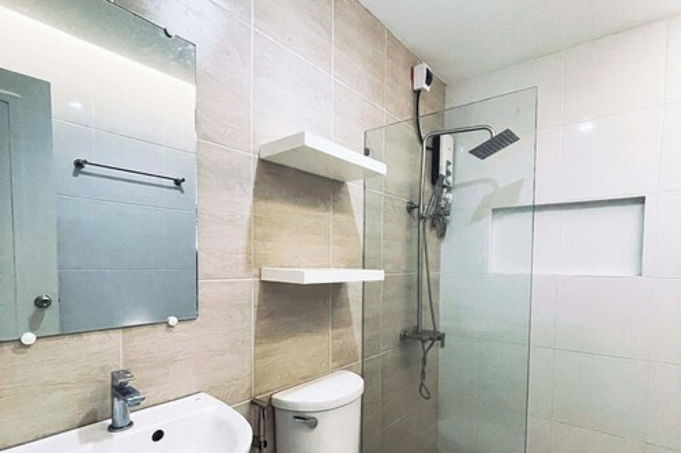 A modern bathroom with a sink, mirror, toilet, and glass-enclosed shower.
