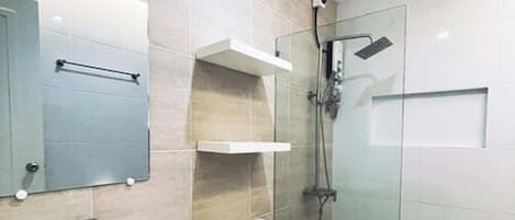 A modern bathroom with a sink, mirror, toilet, and glass-enclosed shower.
