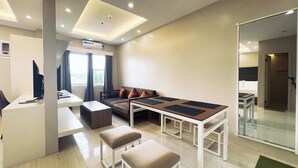 A modern hotel room with a desk, sofa, ottomans, and a dining table. - Daraga Tourist Inn (Daraga)