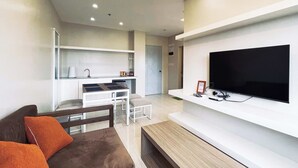 A modern living room with a flat-screen TV, a sofa, and a dining area with a table and chairs. - Daraga Tourist Inn (Daraga)