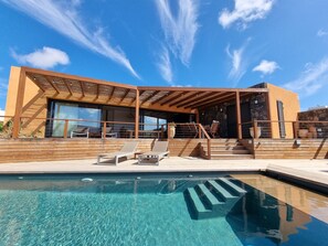 A modern building with a pool, wooden deck, and outdoor seating area. - CASA ESTELLA - Cosy villa in the centre of Lajares with heated pool (Lajares)