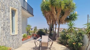 A patio with a table and chairs, surrounded by potted plants and a stone wall. - Impeccable 3-bed Villa in Nicosia (Agia Varvara)