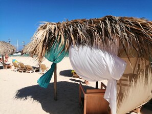Relax in a shaded beachside retreat with a thatched-roof structure and lounge chairs.