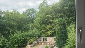 A view of a historic stone structure surrounded by lush greenery, viewed from a window. - Immensee II Apartment with lake view and located at the forest edge (Ronshausen)