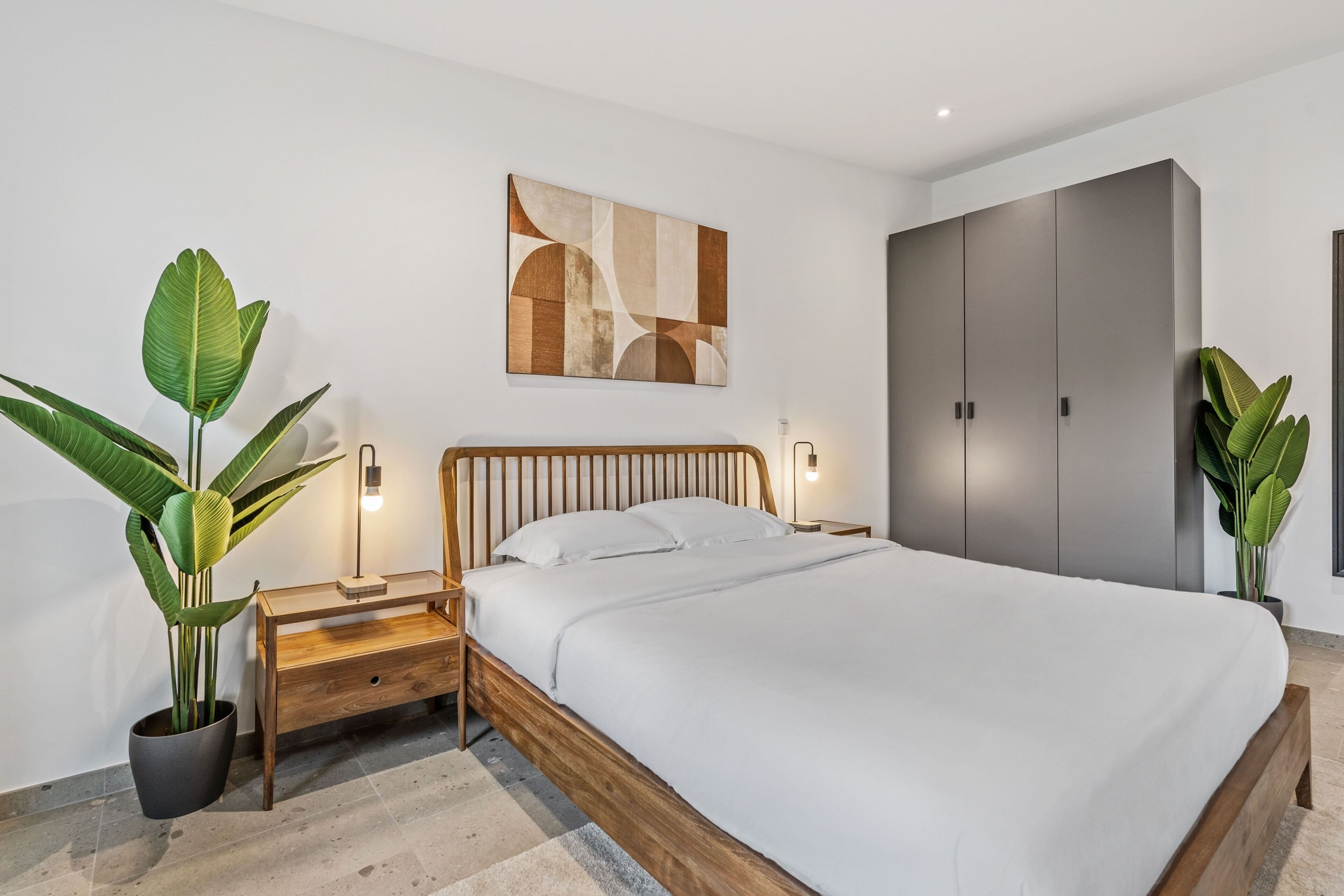 Un dormitorio moderno con una cama de madera, un armario gris y dos plantas en macetas.