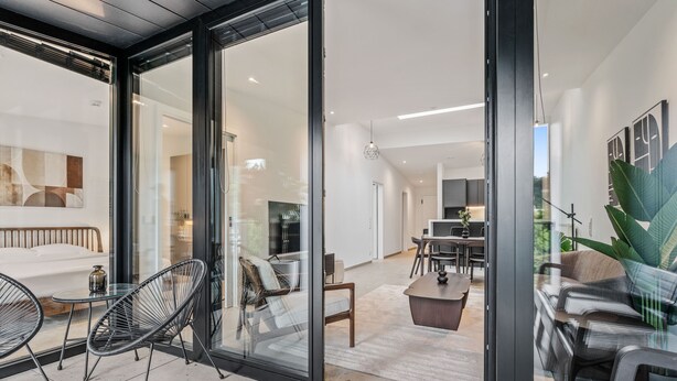 Een modern interieur met een glazen deur naar een eethoek, een bank en een salontafel.