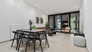 Een moderne woonkamer met een eethoek, grote ramen en uitzicht op de omgeving.