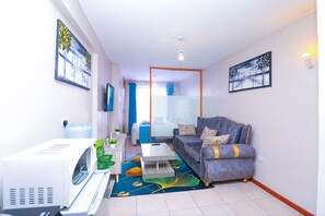 A compact living space with a sofa, a coffee table, a microwave, and a water dispenser. - Songeza Furnished Accomodation-embakasi (Nairobi)