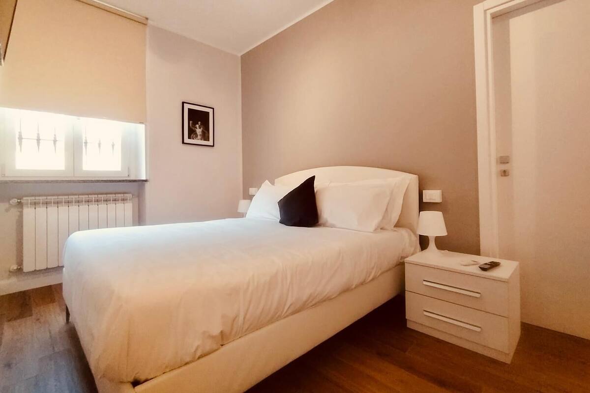 A bedroom with a bed, bedside table, and a radiator.