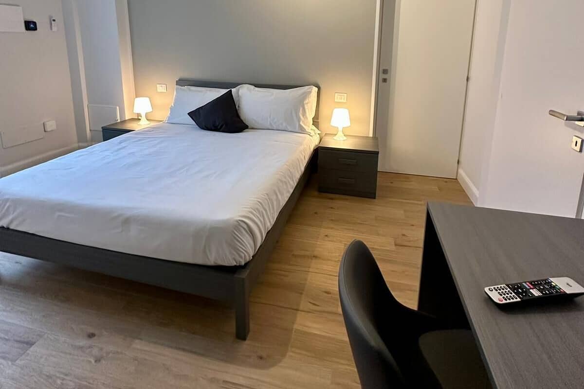 Une chambre moderne équipée d’un lit, de lampes de chevet, d’un bureau et d’un appareil de climatisation.