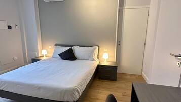 Une chambre moderne équipée d’un lit, de lampes de chevet, d’un bureau et d’un appareil de climatisation.