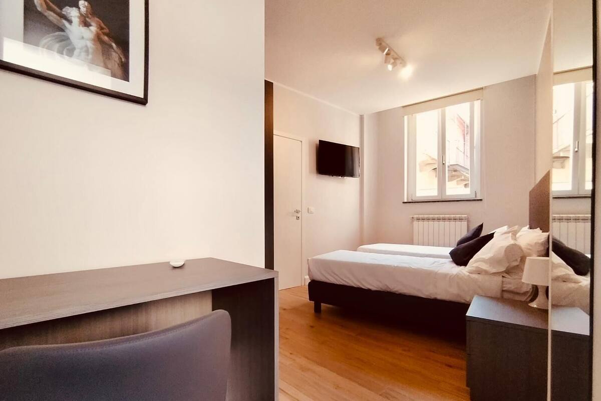 A modern bedroom with a bed, bedside table, and a desk with a chair.