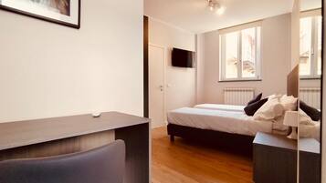 A modern bedroom with a bed, bedside table, and a desk with a chair.