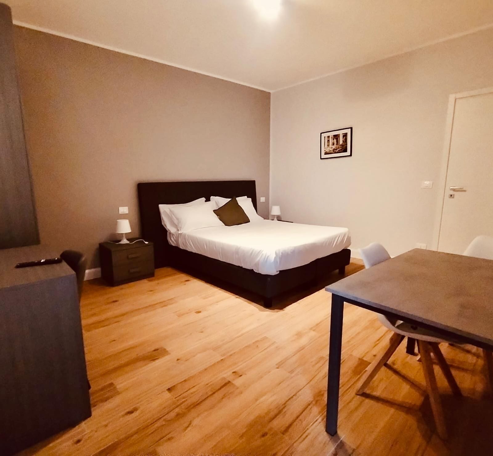 A bedroom with a bed, bedside tables, a desk, and a chair.