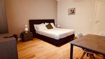 A bedroom with a bed, bedside tables, a desk, and a chair.