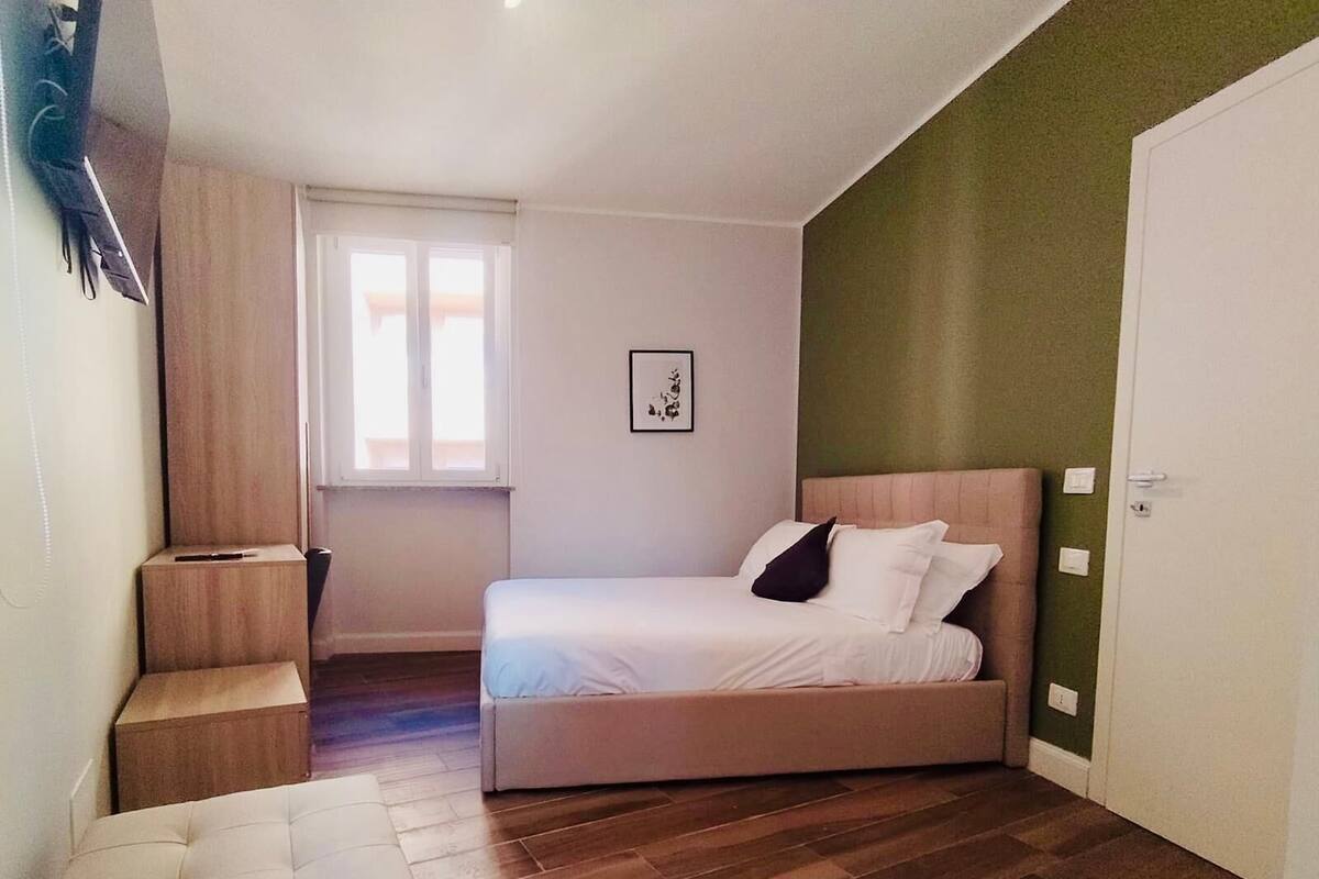 A bedroom with a bed, a nightstand, a window, and a door.