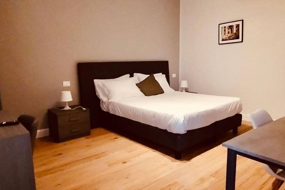 A bedroom with a bed, bedside tables, a desk, and a chair.