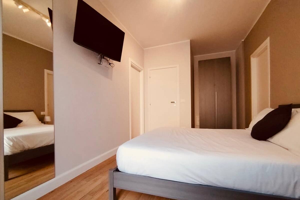 Une chambre à coucher avec un lit, un téléviseur à écran plat fixé au mur et un plancher en bois.
