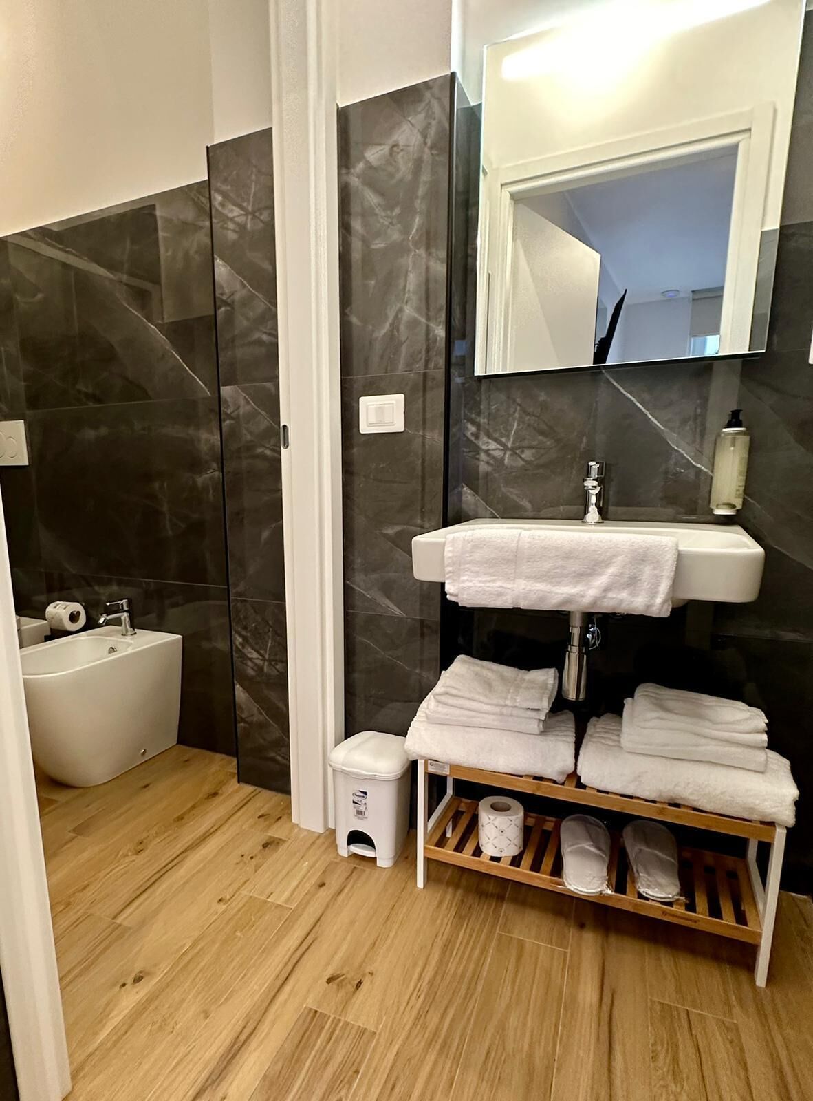 A modern bathroom with a white sink, mirror, and towel rack.