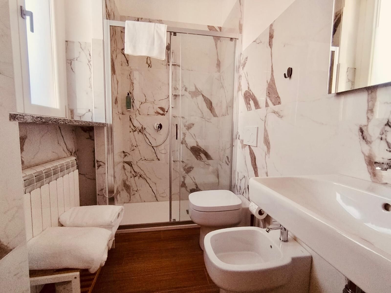 Un bagno con doccia in marmo, un water, un bidet e un lavandino.