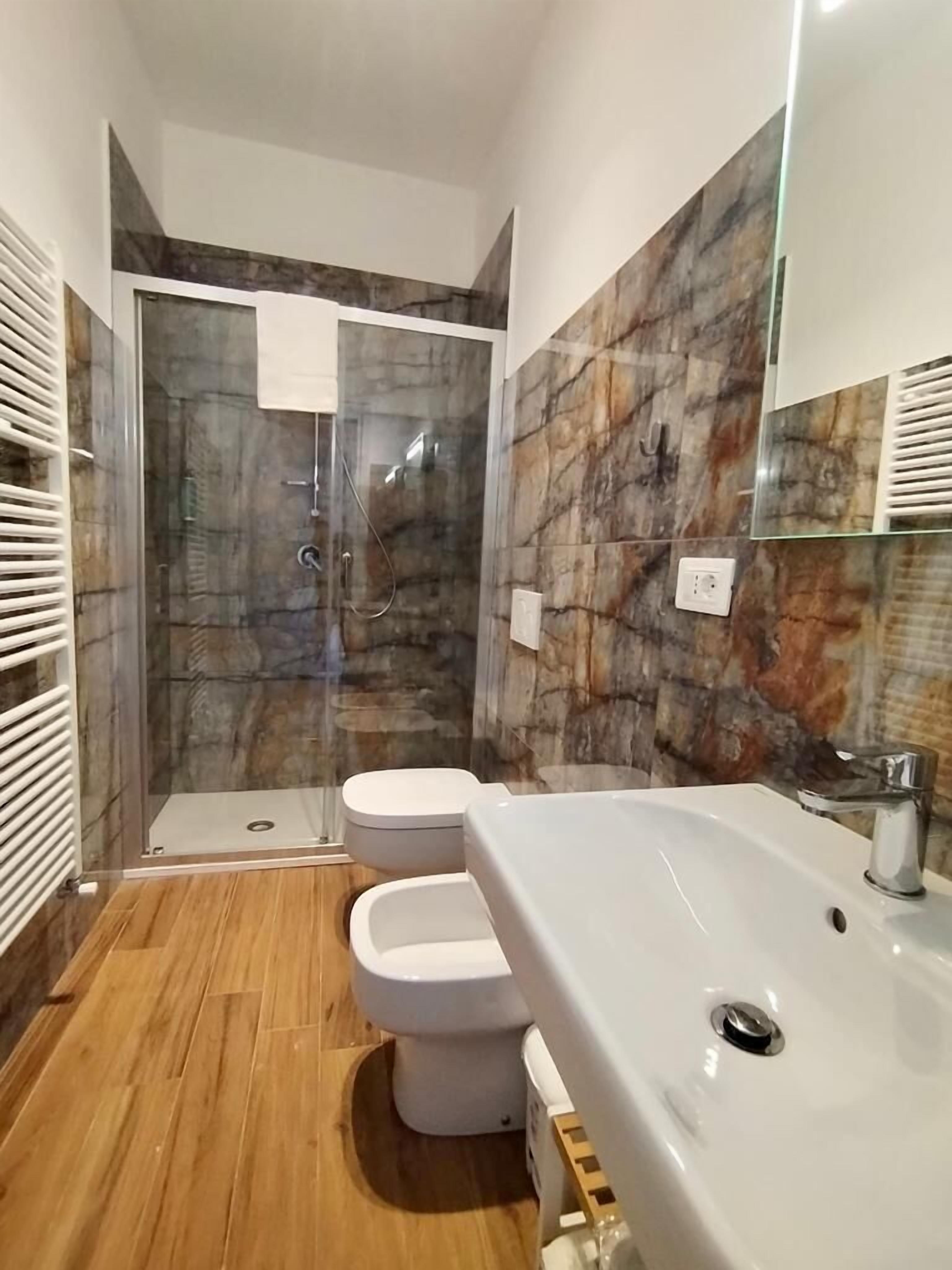 Une salle de bain moderne avec une douche à parois de verre, deux toilettes et un grand lavabo.