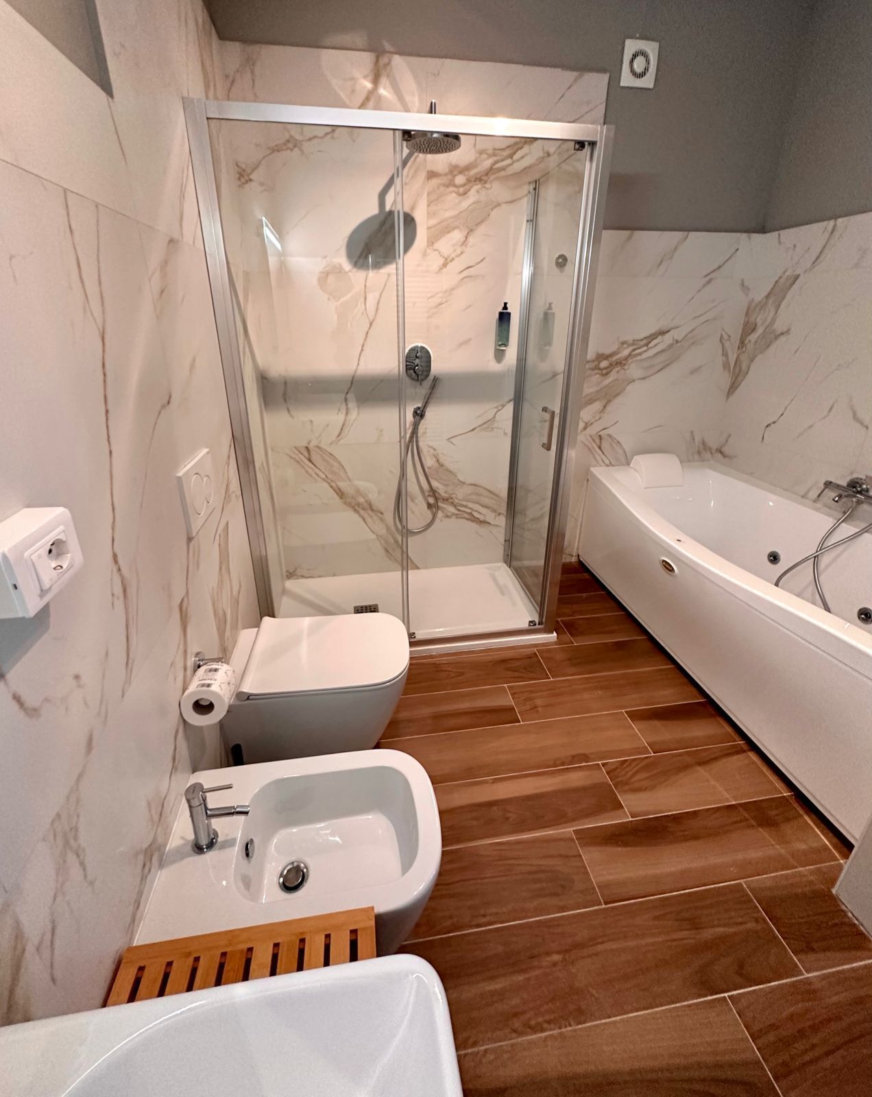 Un bagno moderno con doccia a vetro, vasca da bagno indipendente, lavabo su piedistallo e un water.