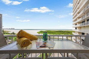 A balcony with a table, a rolled towel, a magazine, and a bottle of water.
