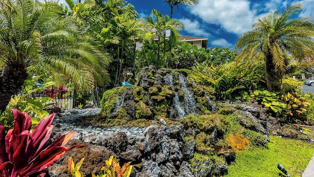 A tropical garden with a waterfall, lush greenery, and a clear blue sky. - Grand Champions 30 Golf course views (Wailea)