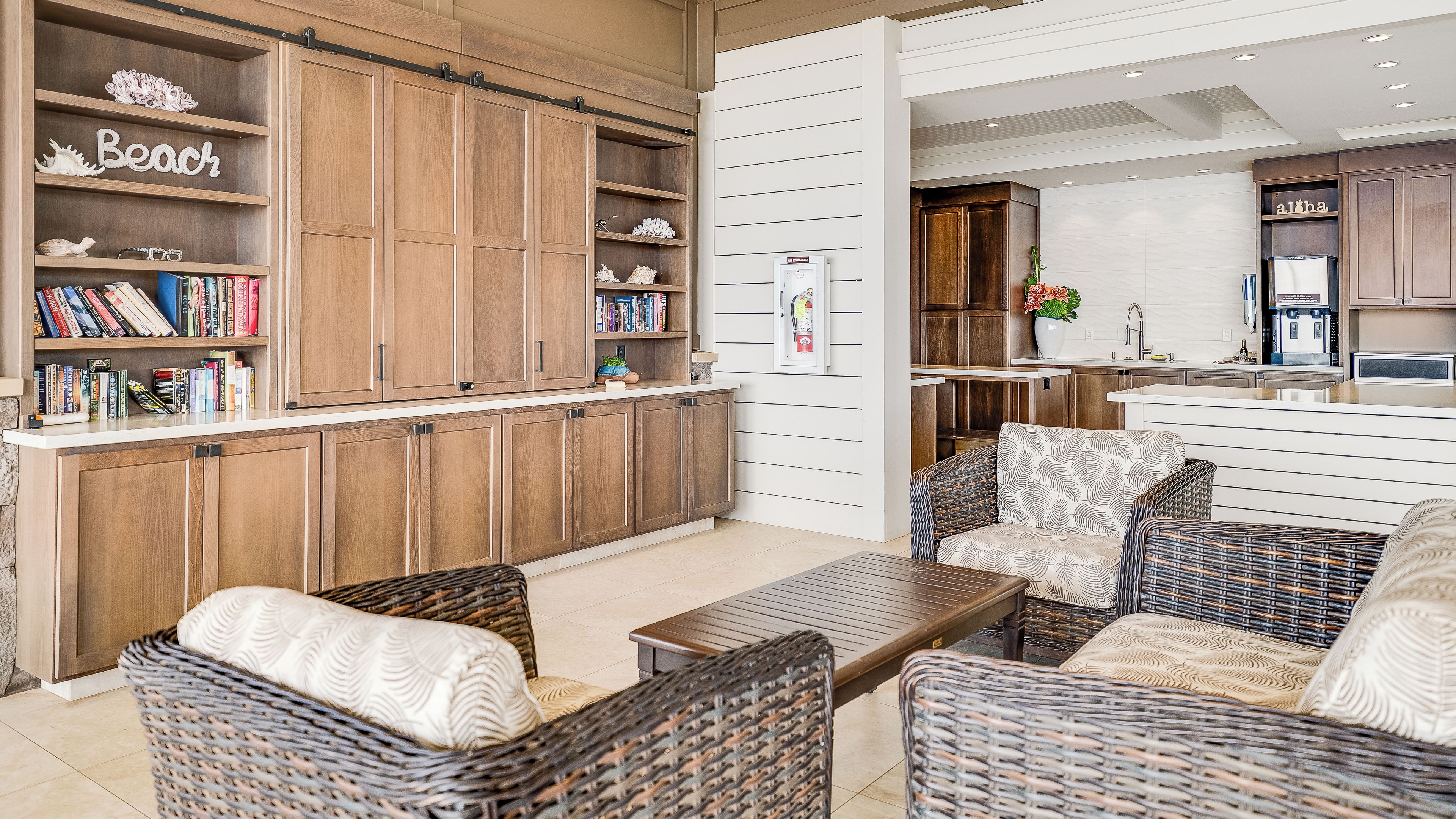 A modern kitchen with wooden cabinets, a built-in island, and a seating area with wicker furniture.