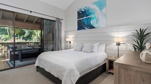 Une chambre dotée d’un grand lit, d’une table de chevet, d’une lampe fixée au mur et offrant une vue sur un balcon aménagé avec du mobilier d’extérieur.