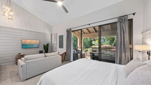 Une chambre moderne avec un grand lit, un canapé, une télévision et un balcon donnant sur un paysage verdoyant.