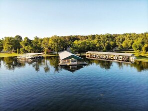 A lakeside dock with a covered seating area and a boat.