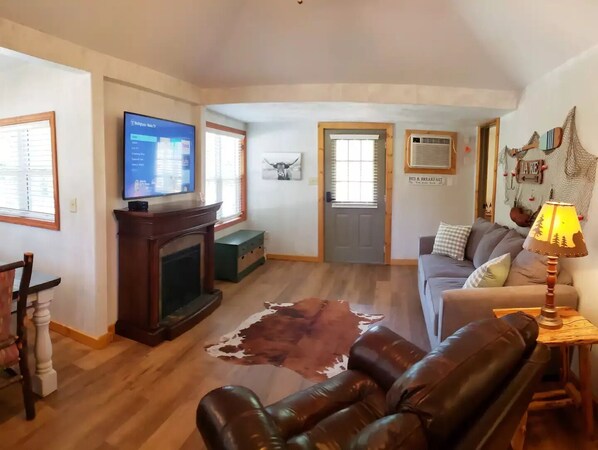 A living room with a fireplace, leather sofa, and a television.