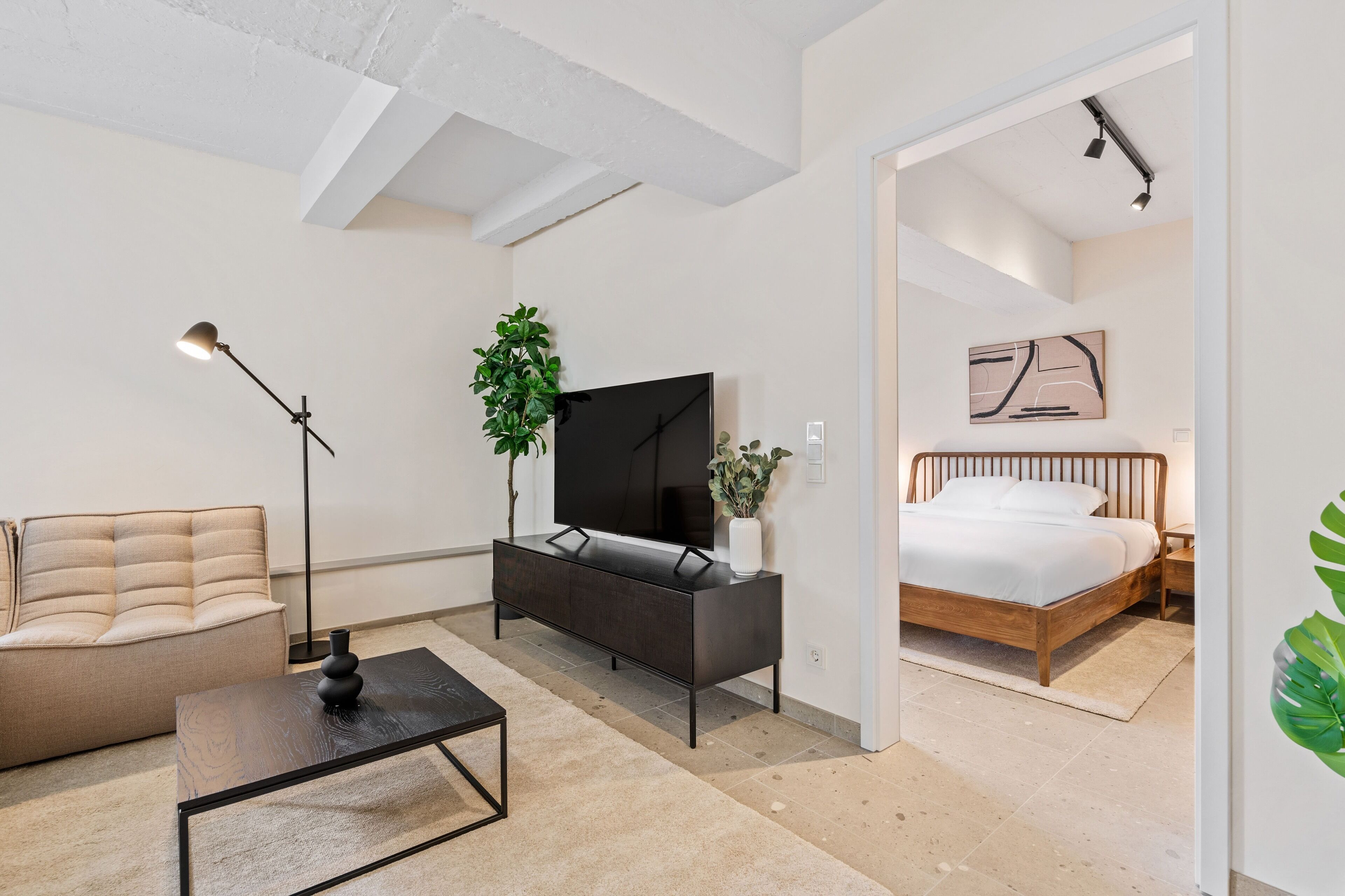 A modern bedroom with a bed, bedside table, and a TV.